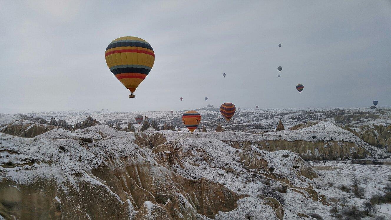 Hot air balloons flying over snow-dusted Cappadocia valleys in winter